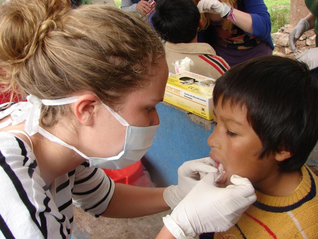 A young boy goes through a dental check up with medical volunteers in Peru. Projects Abroad volunteer checks the dental health of a young boy during a medical outreach in Peru.